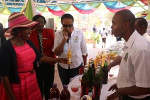 A JKUAT Food Science exhibitor explains to Mrs. Ruto how value addition of various food products such as juice, yoghurt, wine and jam is done at JKUAT.